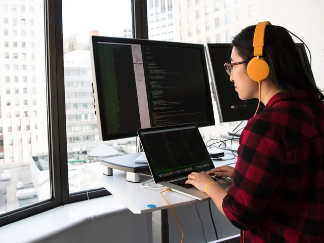 Junior vállalati Java backend fejlesztő két monitoron dolgozik egy irodai munkaállomáson